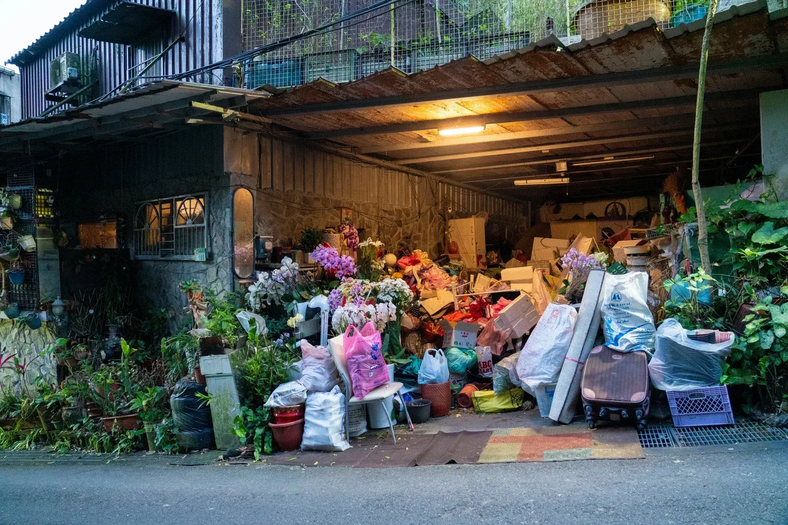 A garage filled with lots of junk and flowers.