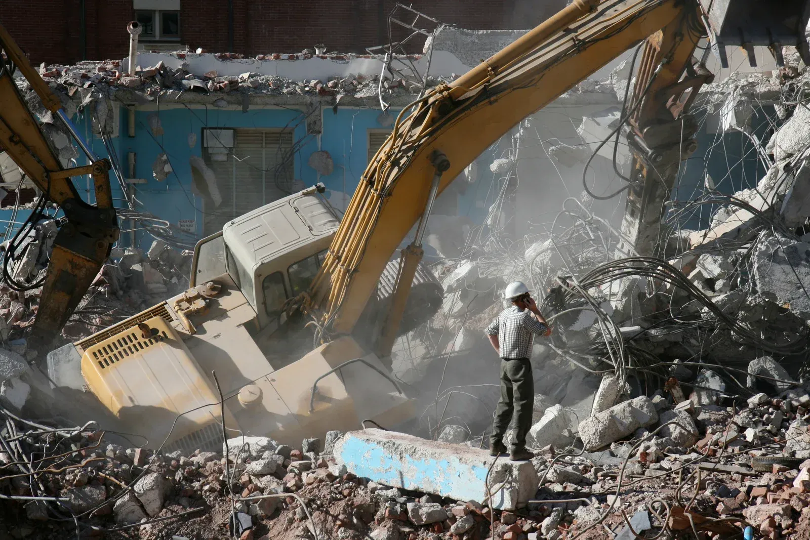 A large yellow excavator is demolishing a building.