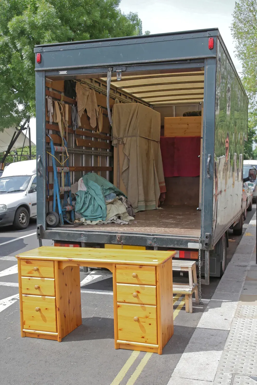 A wooden desk is sitting in front of a moving truck
