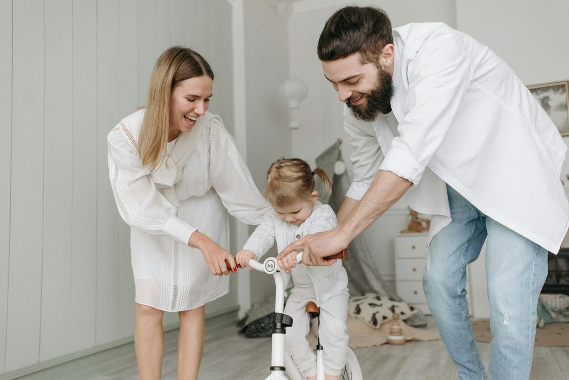 A man and woman are holding a little girl in their arms.