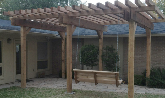 A wooden pergola with a swing underneath it