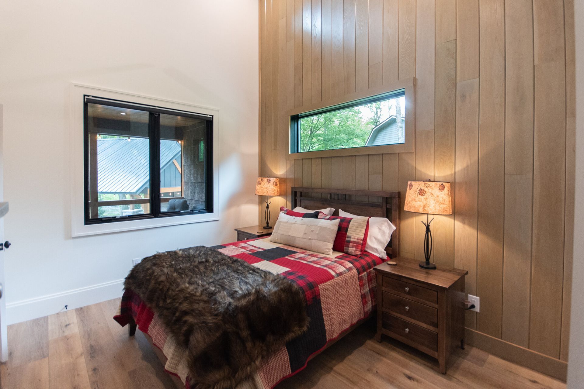 Cozy bedroom with wood-paneled wall, bed, bedside tables, and two lamps