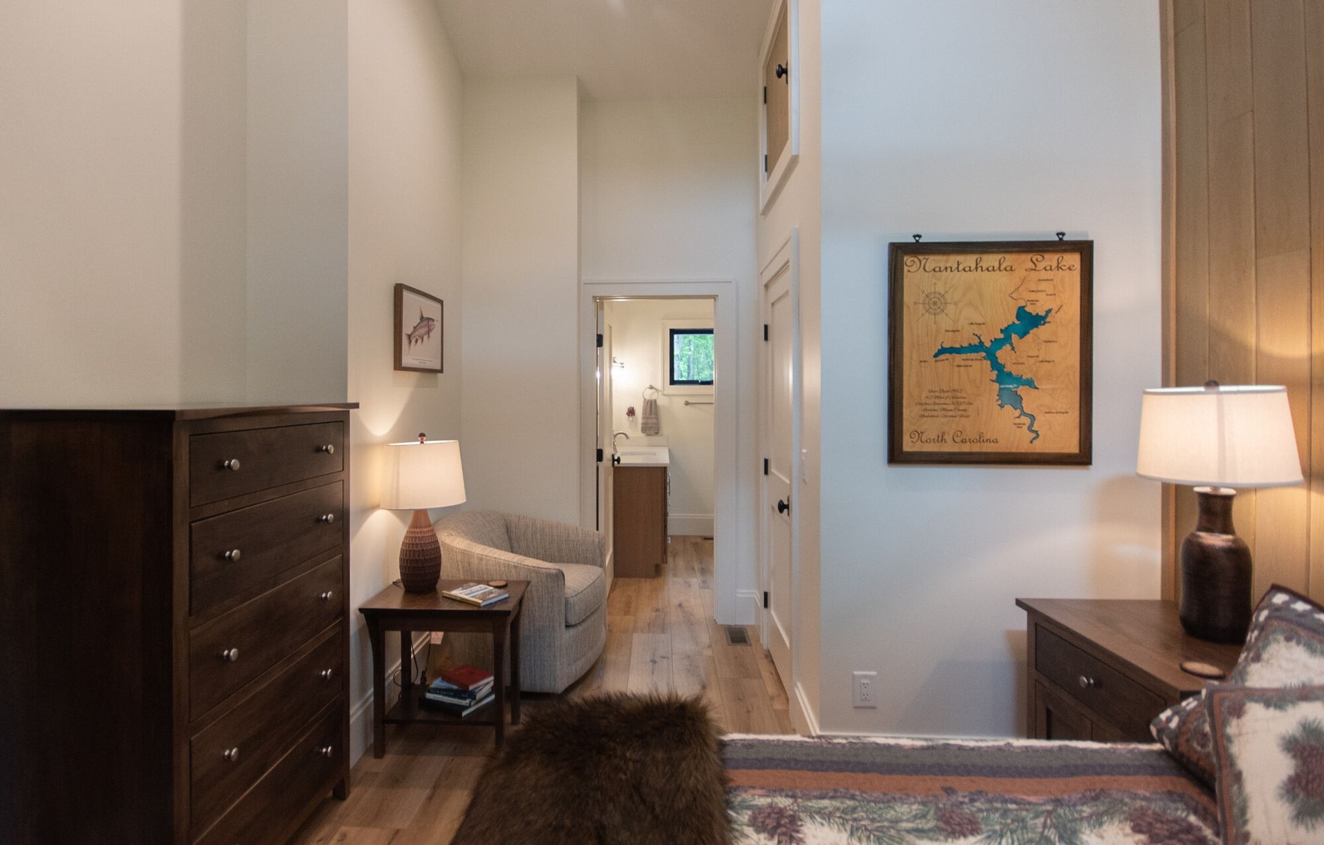 Modern bedroom with dark wood furniture, lamp, hallway, and framed art on the wall