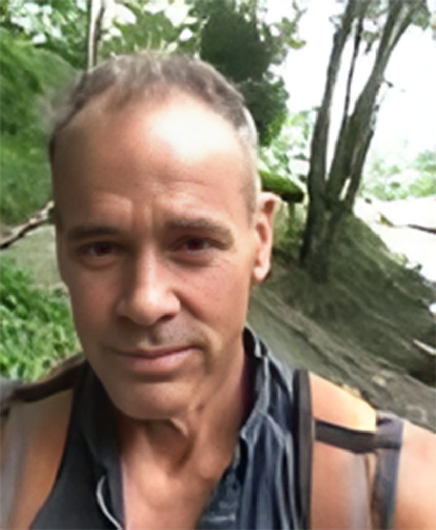 A man with a backpack is standing on a path in the woods.