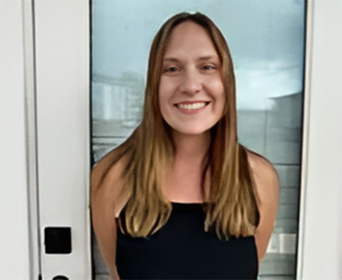 A woman is smiling while standing in front of a door.