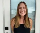 A woman is smiling while standing in front of a door.
