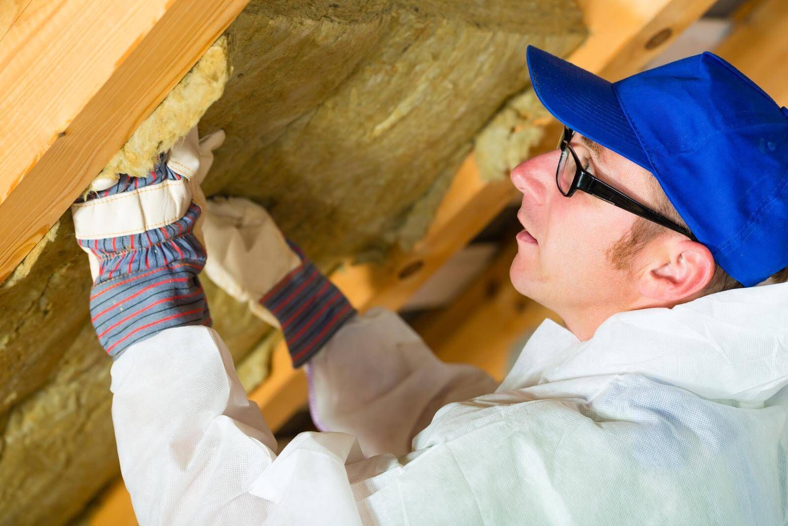 A worker installing insulation into a house 