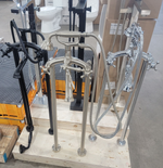 Assorted chrome and black metal railing/handrail posts displayed on a pallet in a warehouse