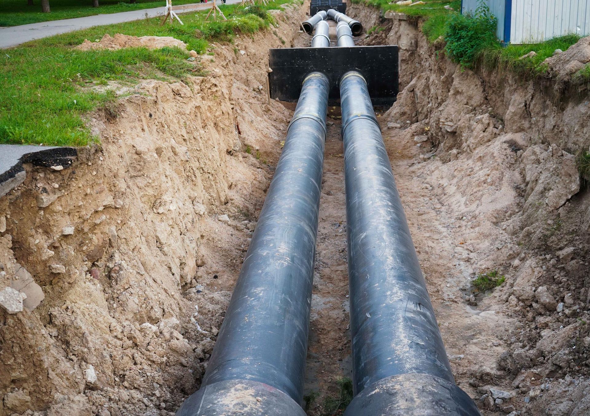 Two pipes are being installed in a trench.