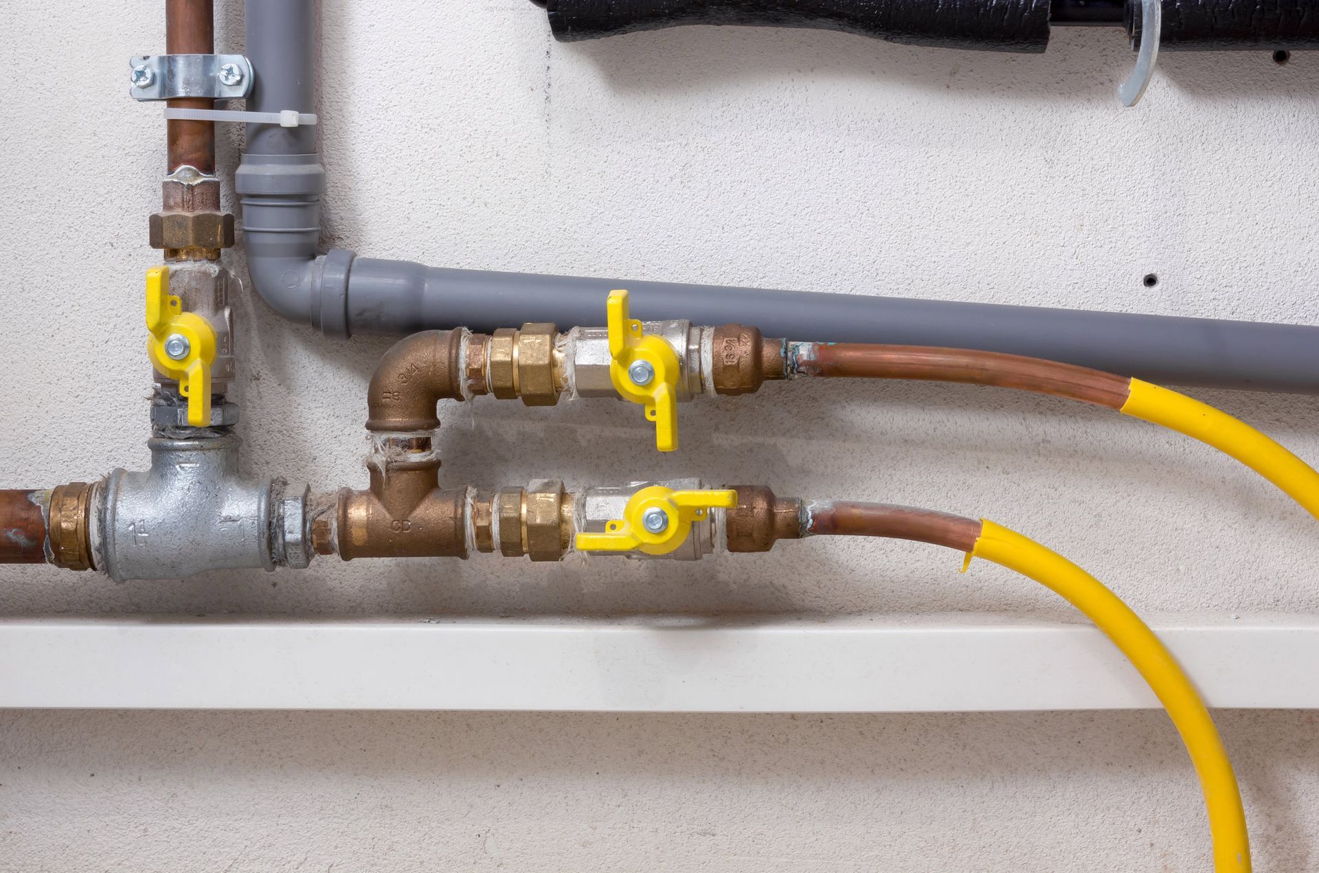 A close up of a gas pipe with yellow valves.
