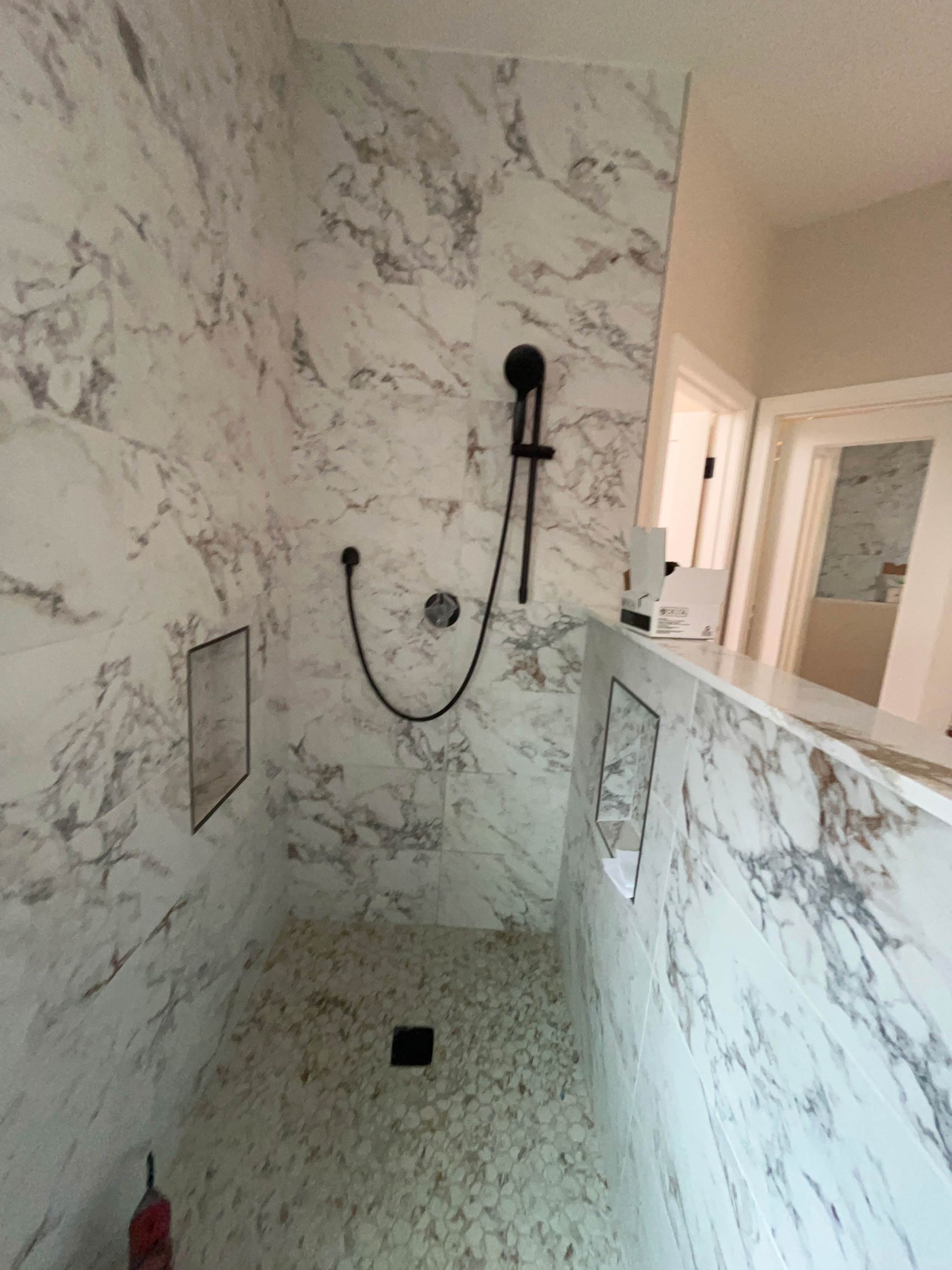 A bathroom with marble walls and a walk in shower.