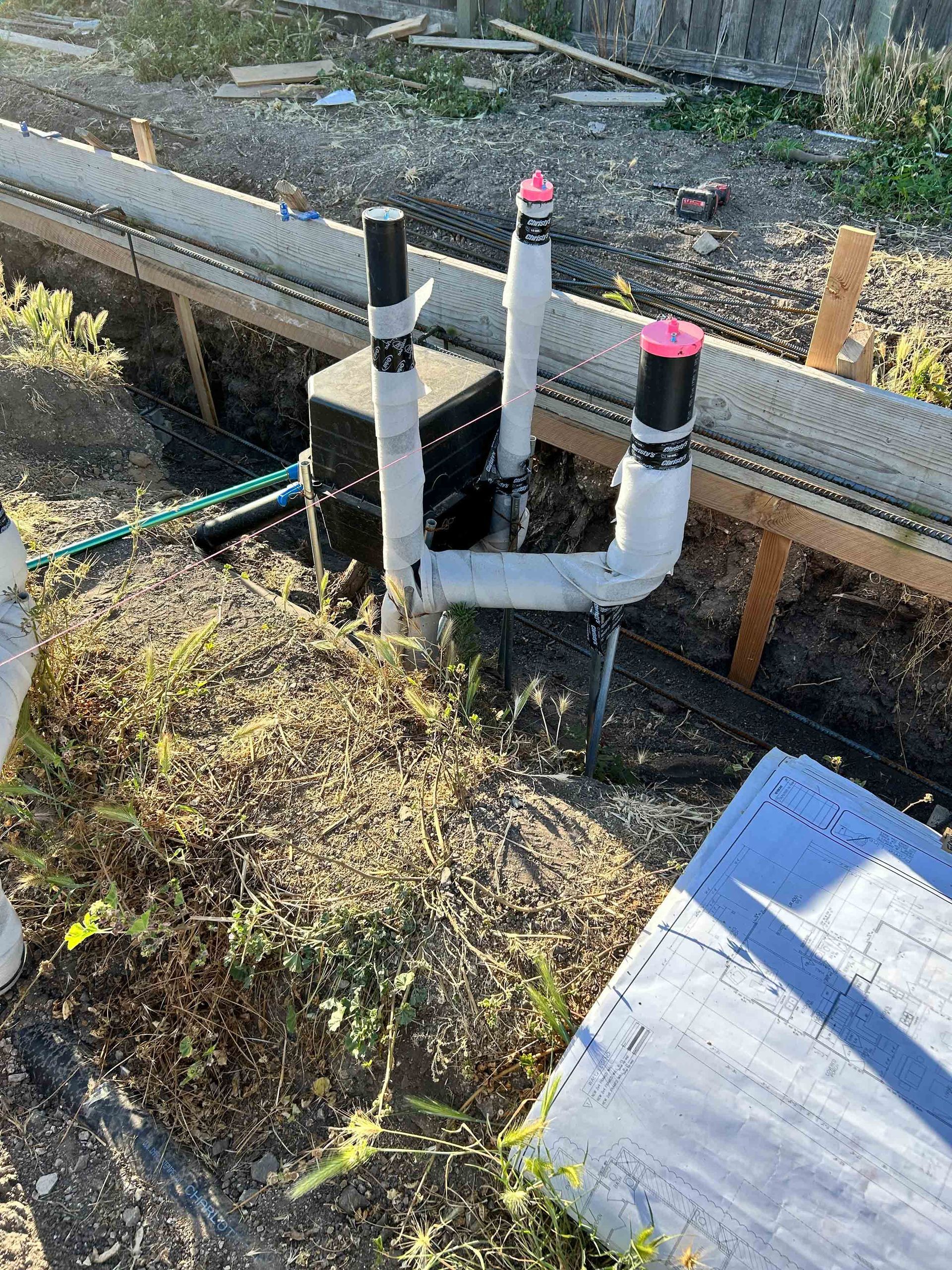 A bunch of pipes are sitting on top of a pile of dirt.