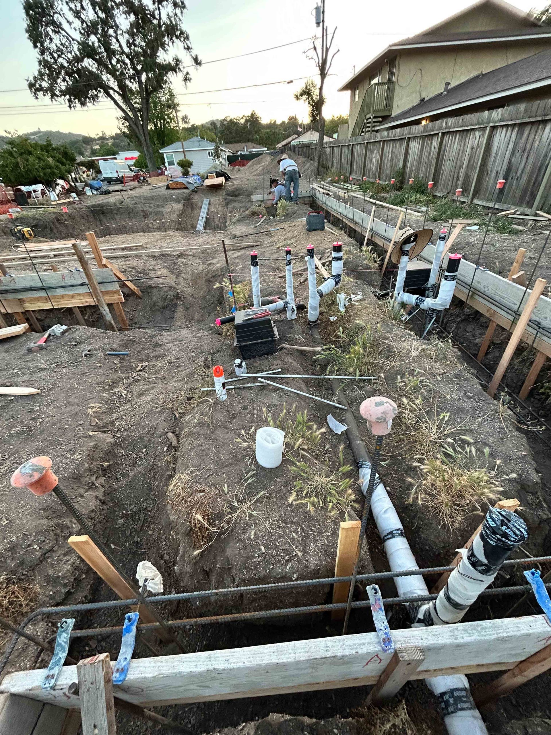 The inside of a house under construction with wooden beams and pipes.