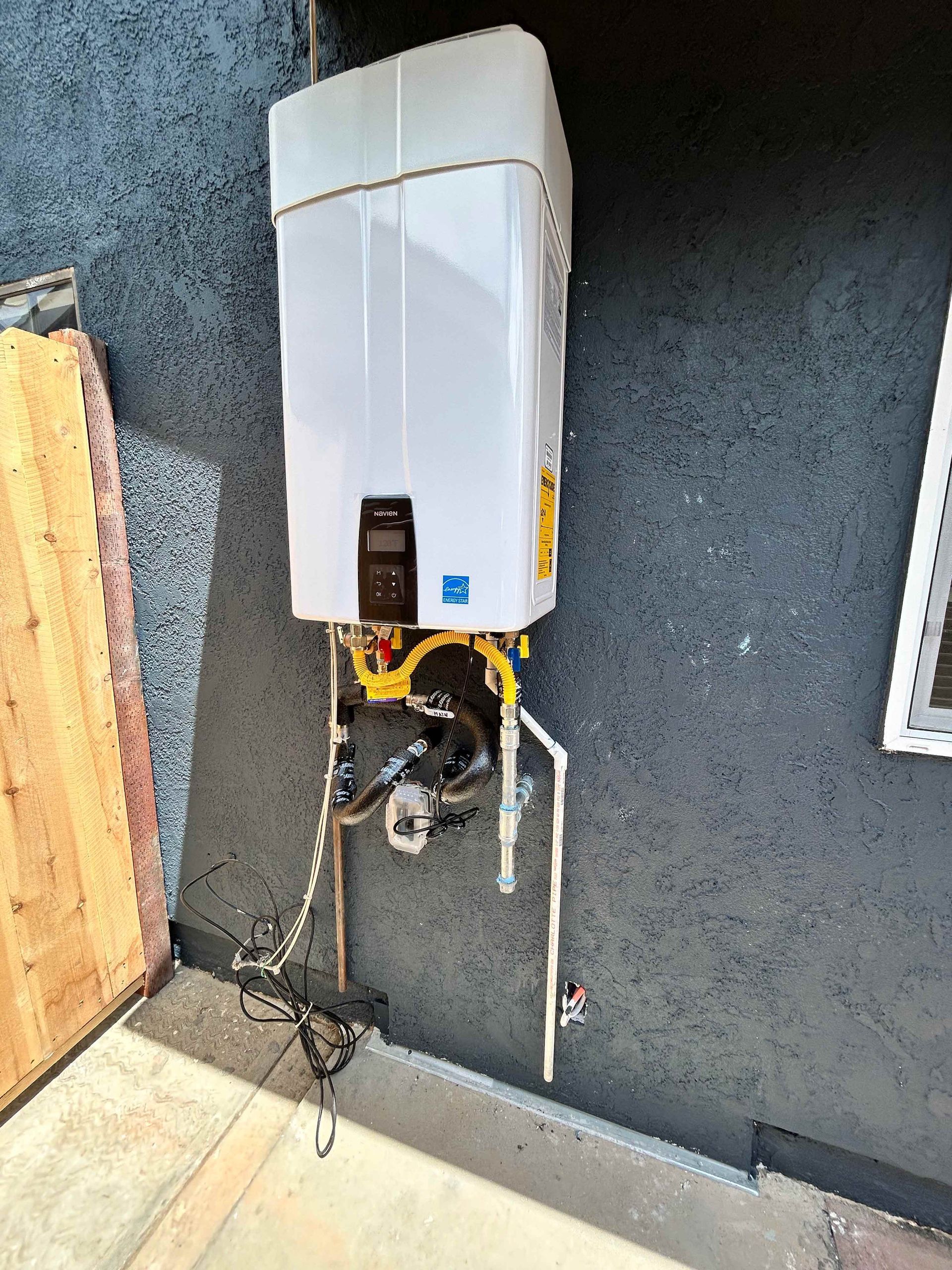 A white water heater is hanging on the side of a building.