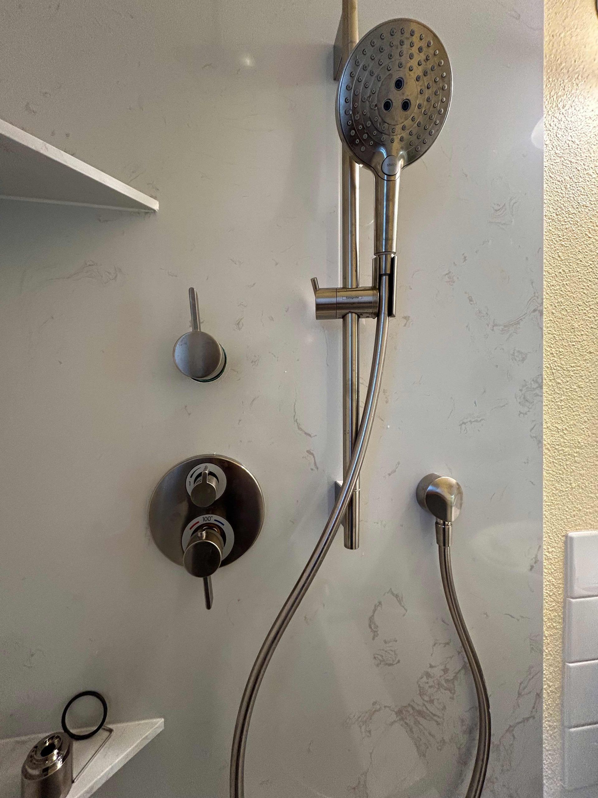 A shower head is hanging on a wall in a bathroom.