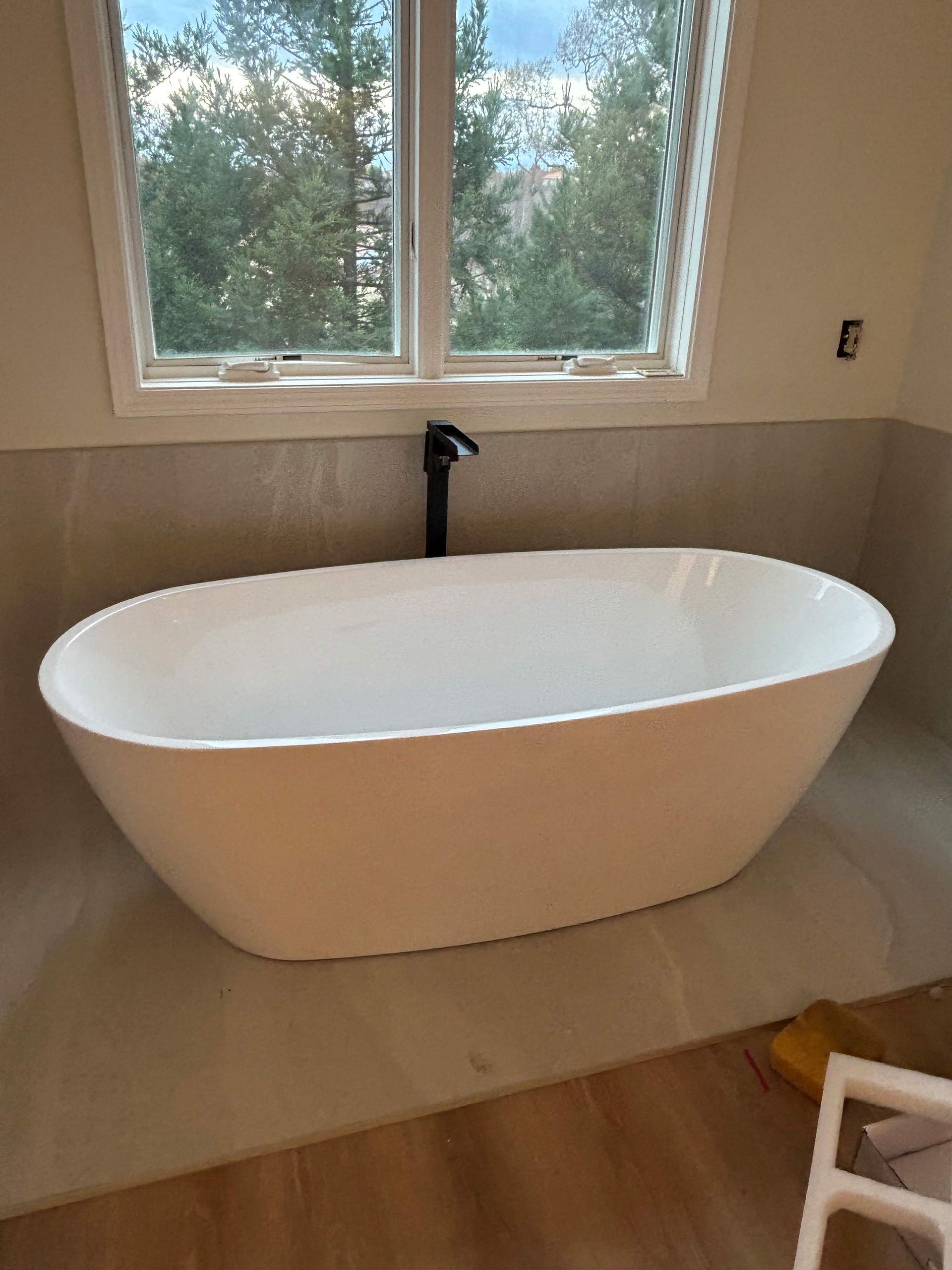 A white bathtub is sitting in a bathroom next to a window.