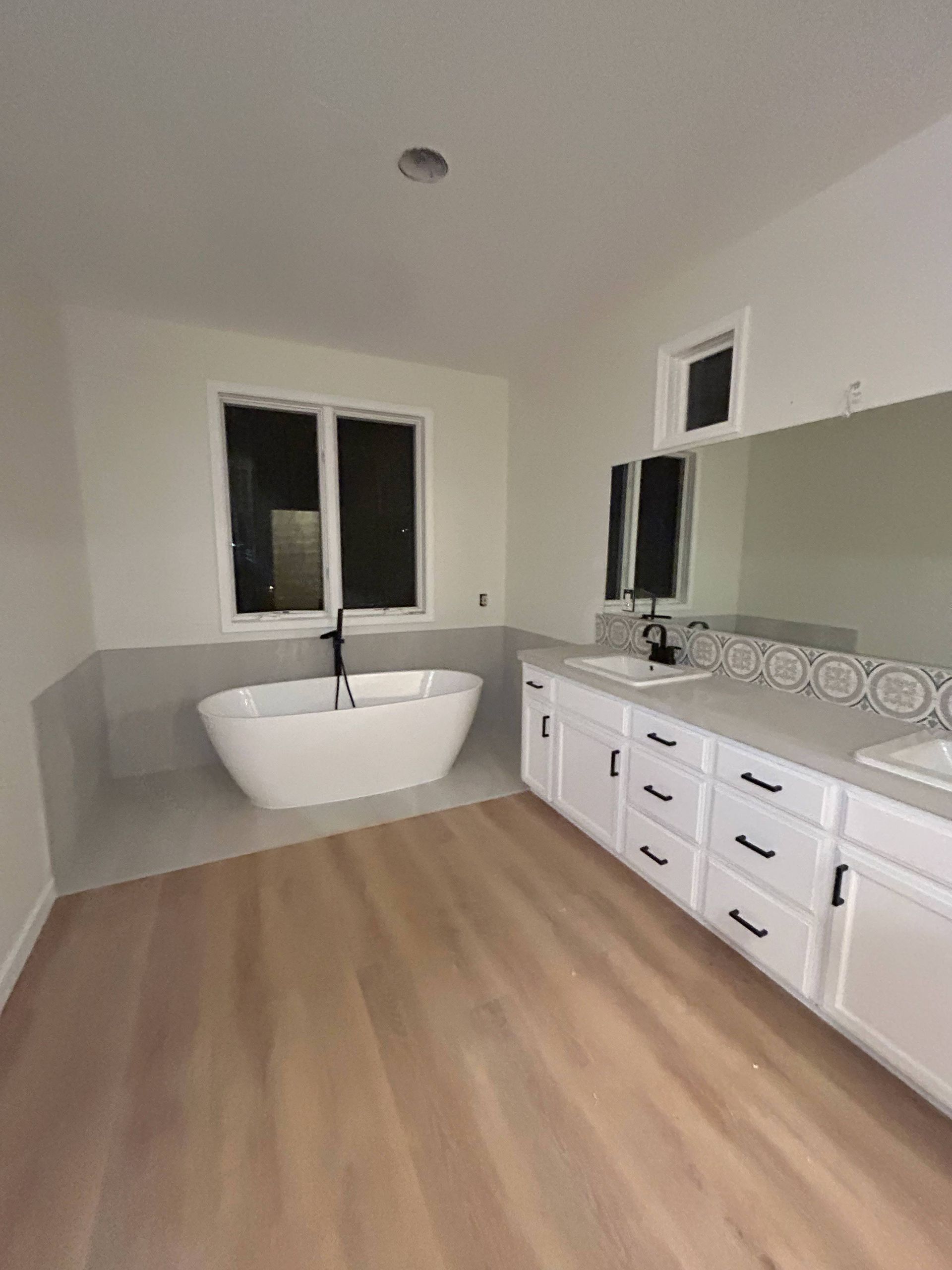 A bathroom with a tub, sink and mirror.