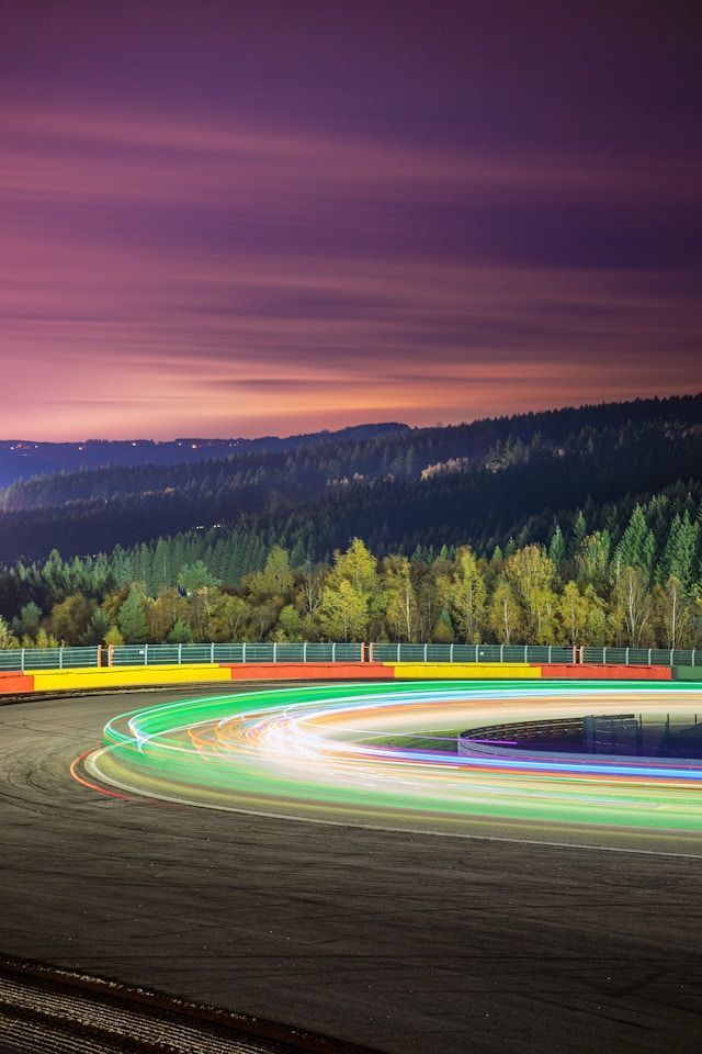 Formula 1 race track is lit up at night with a sunset in the background.