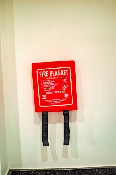 A red fire blanket is hanging on a white wall