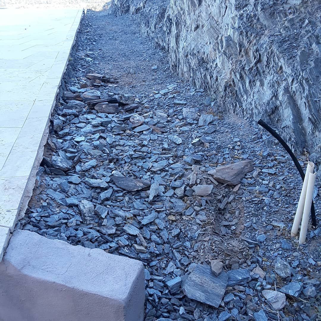 A pile of rocks is sitting next to a stone wall.
