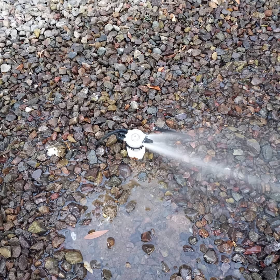 A sprinkler is spraying water on a pile of rocks.