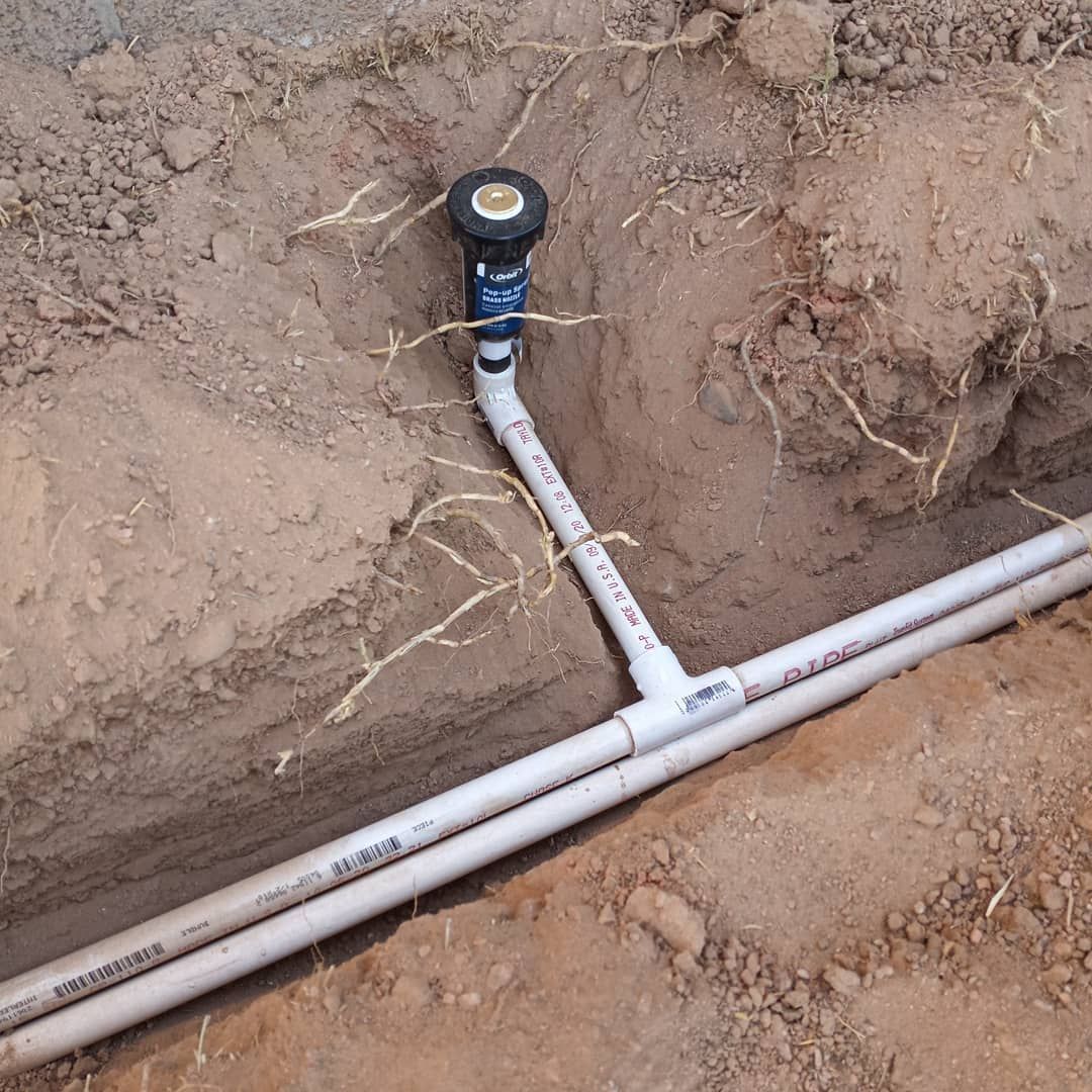 A sprinkler is attached to a pipe in the dirt