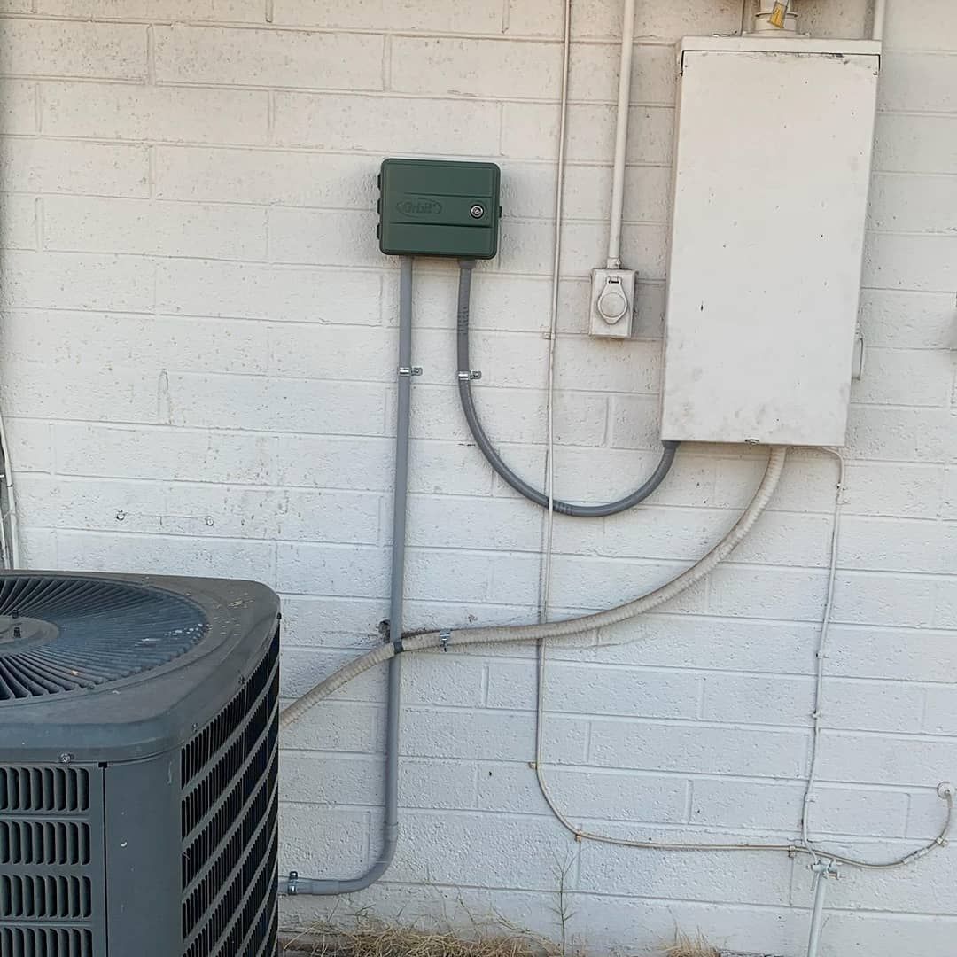 An air conditioner is sitting on the side of a white brick building.