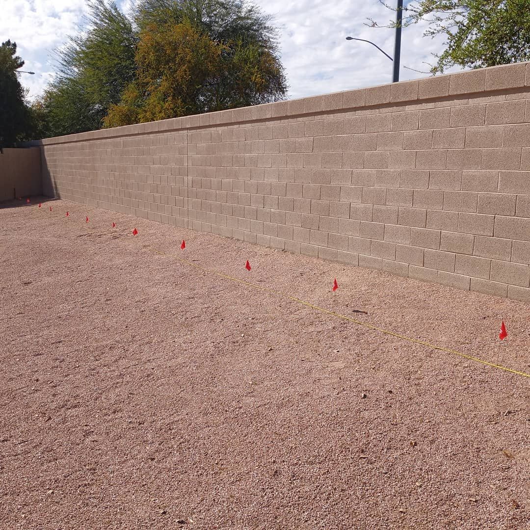 A brick wall is surrounded by gravel in a backyard.