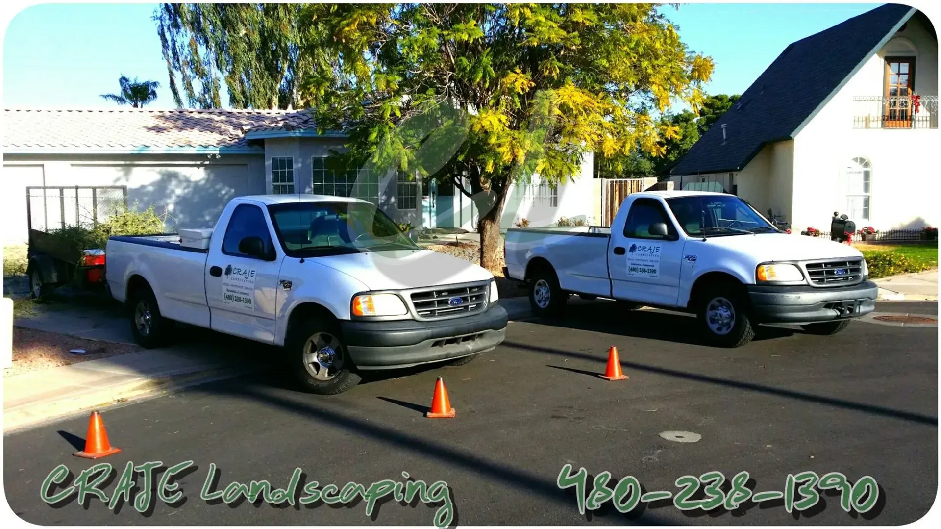 Two white trucks are parked in front of a house