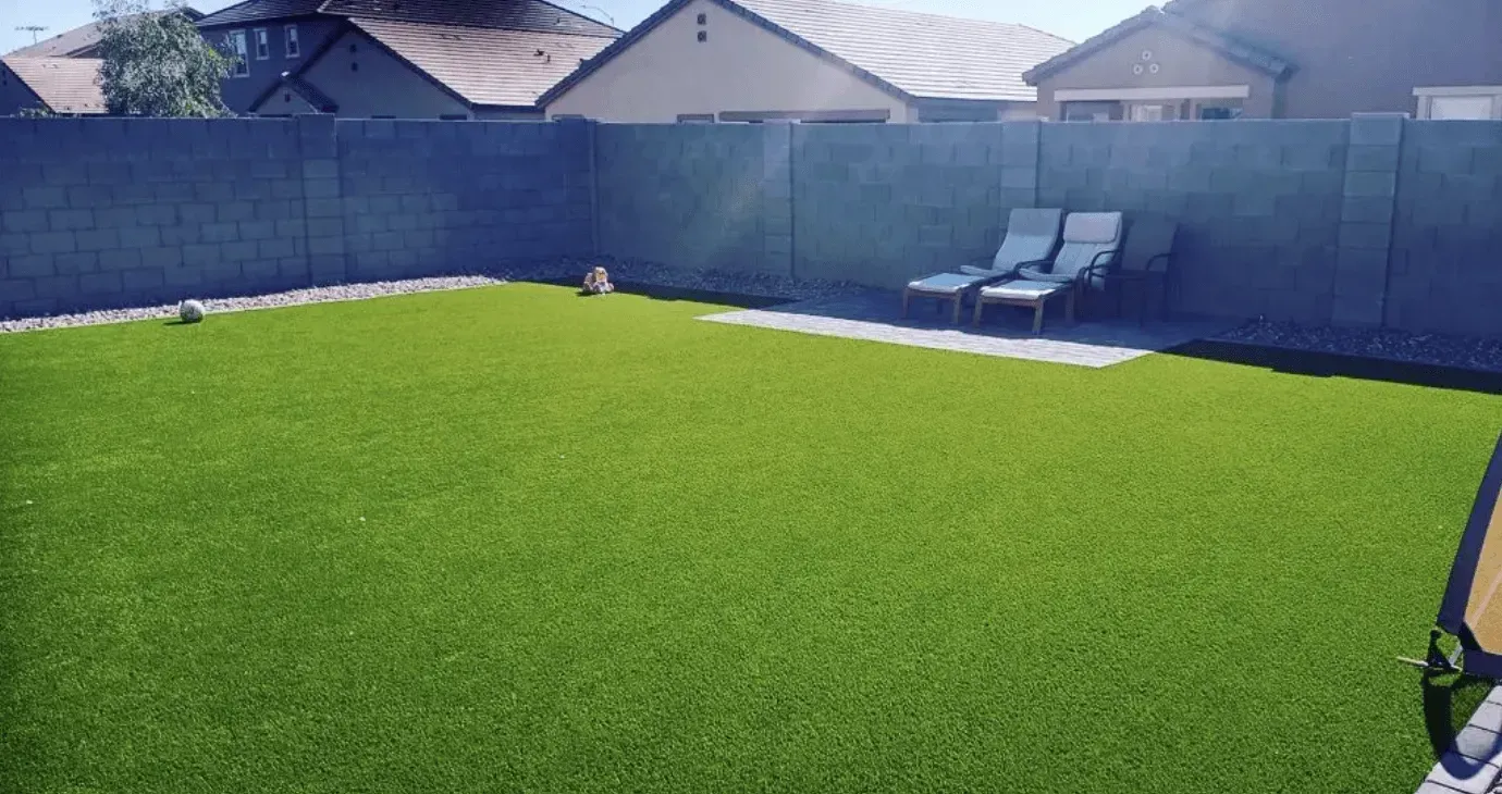 A backyard with a fence and chairs in it.
