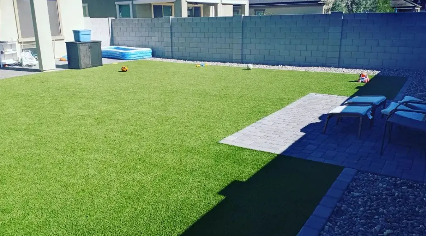A backyard with a lot of grass and a fence.
