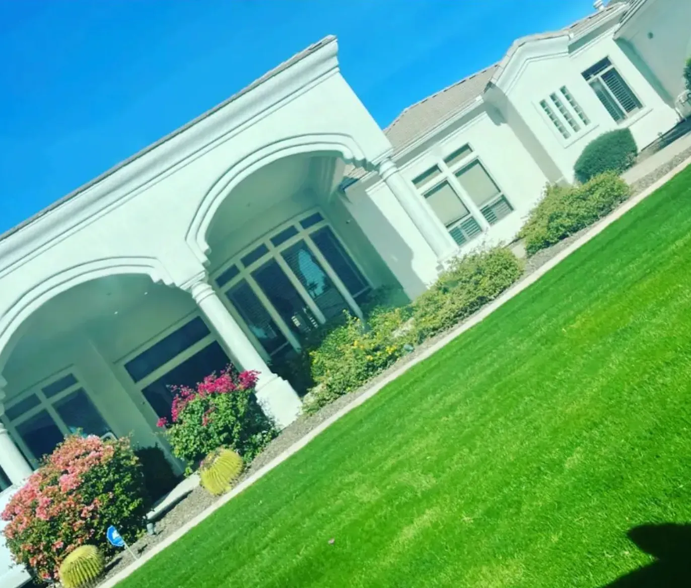 A large white house with a lush green lawn in front of it.