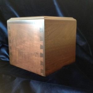 Wooden box, brown and tan, with dovetail joints, sitting on a dark cloth.