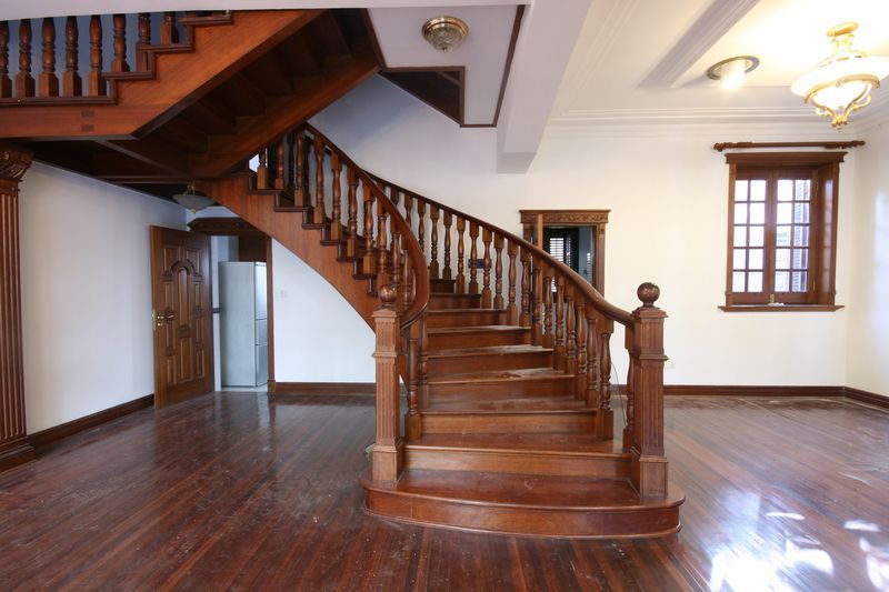 Refinished mahogany curved staircase surrounded by mahogany plank flooring