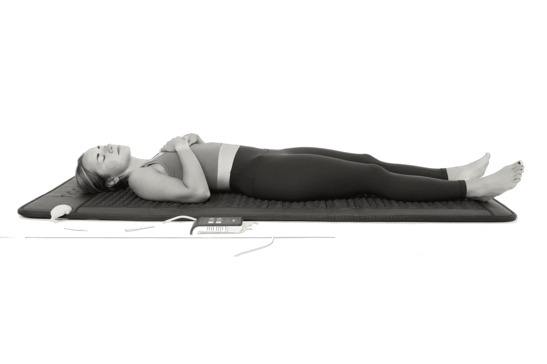 Woman lying on a mat, eyes closed, hands on chest, relaxing.