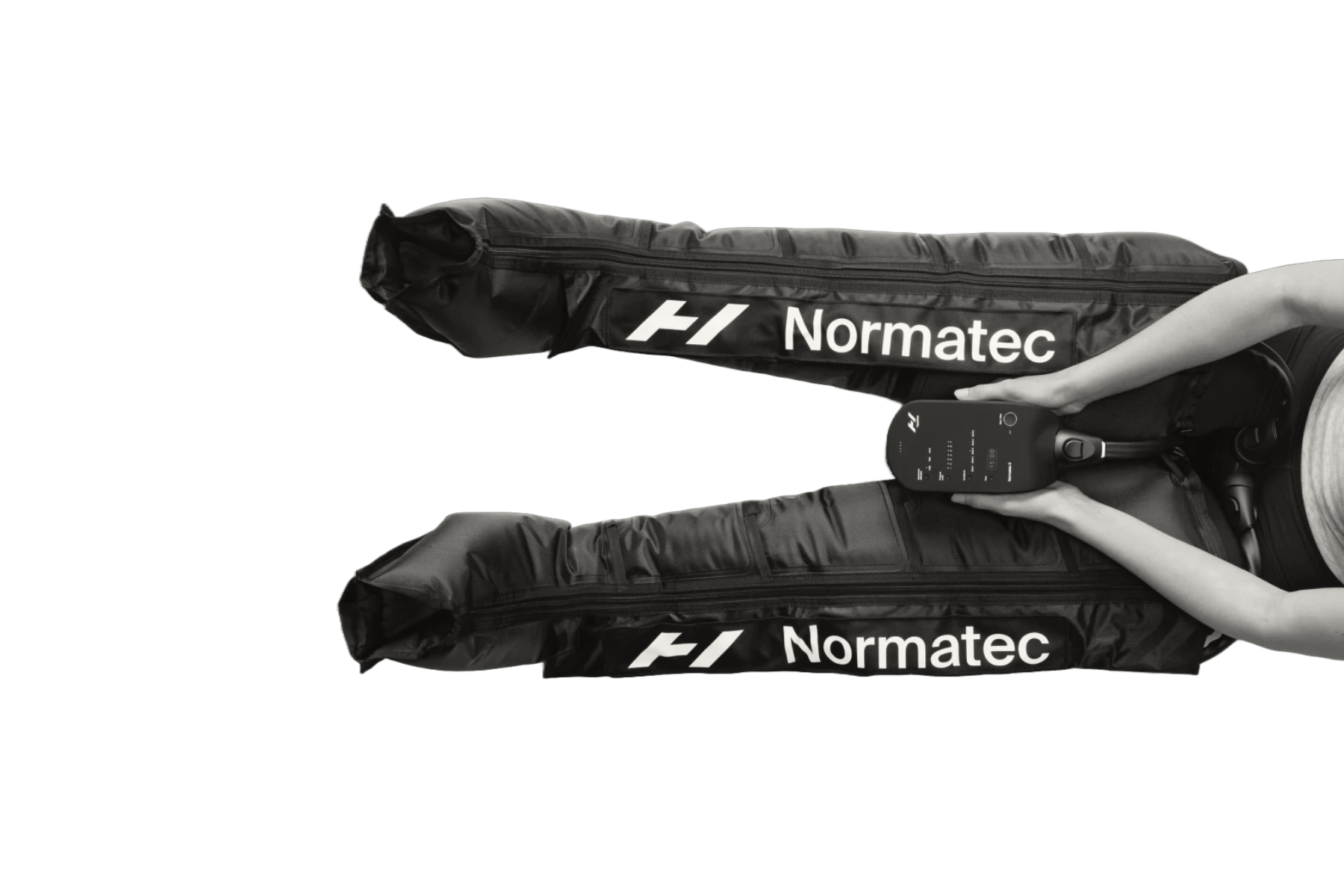 Person using a Normatec leg recovery system. Black sleeves inflate while controlling the device.