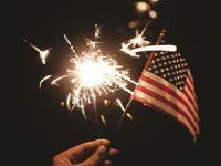 A person is holding a sparkler in front of an american flag.