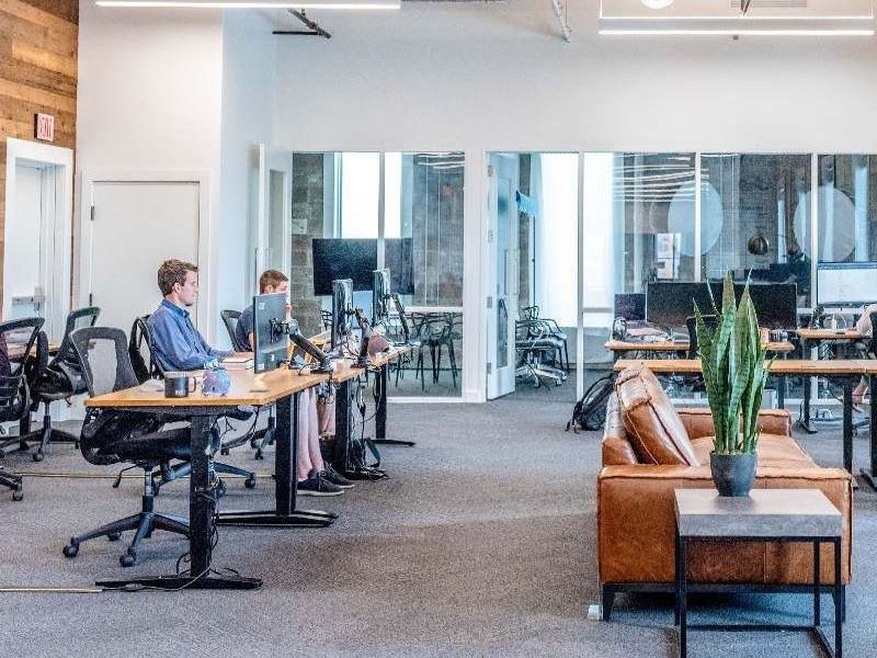 A group of people are sitting at desks in an office.