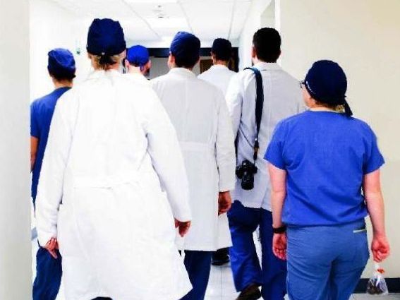 A group of doctors and nurses are walking down a hallway