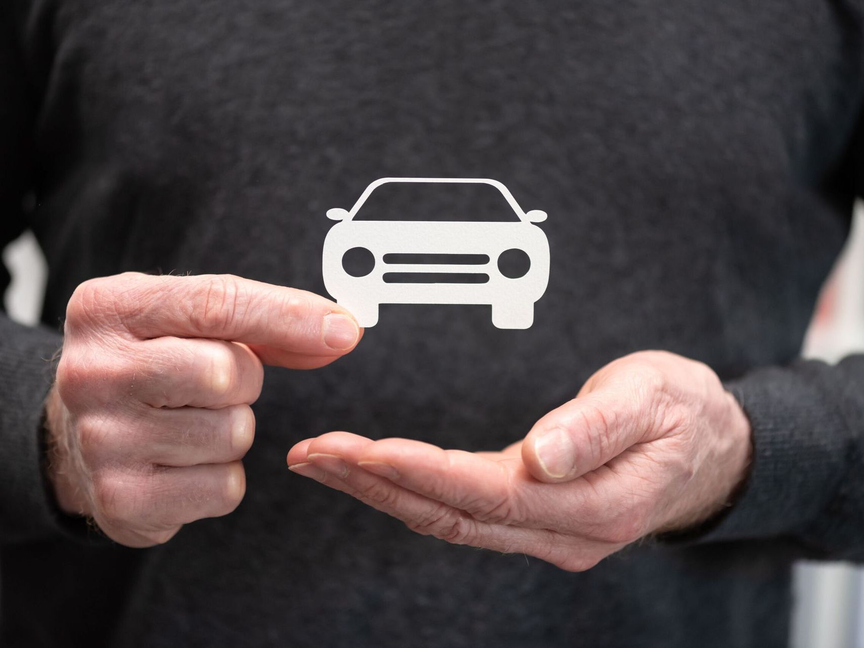 A man is holding a car icon in his hands.