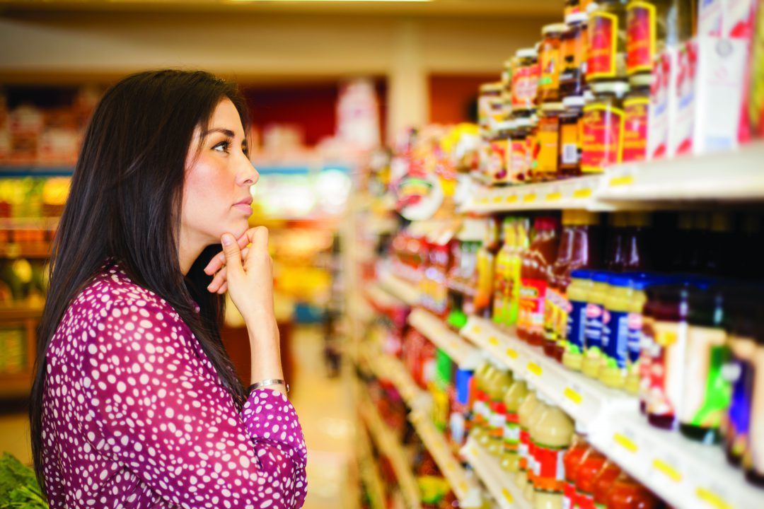 A woman is looking at a shelf in a grocery store.