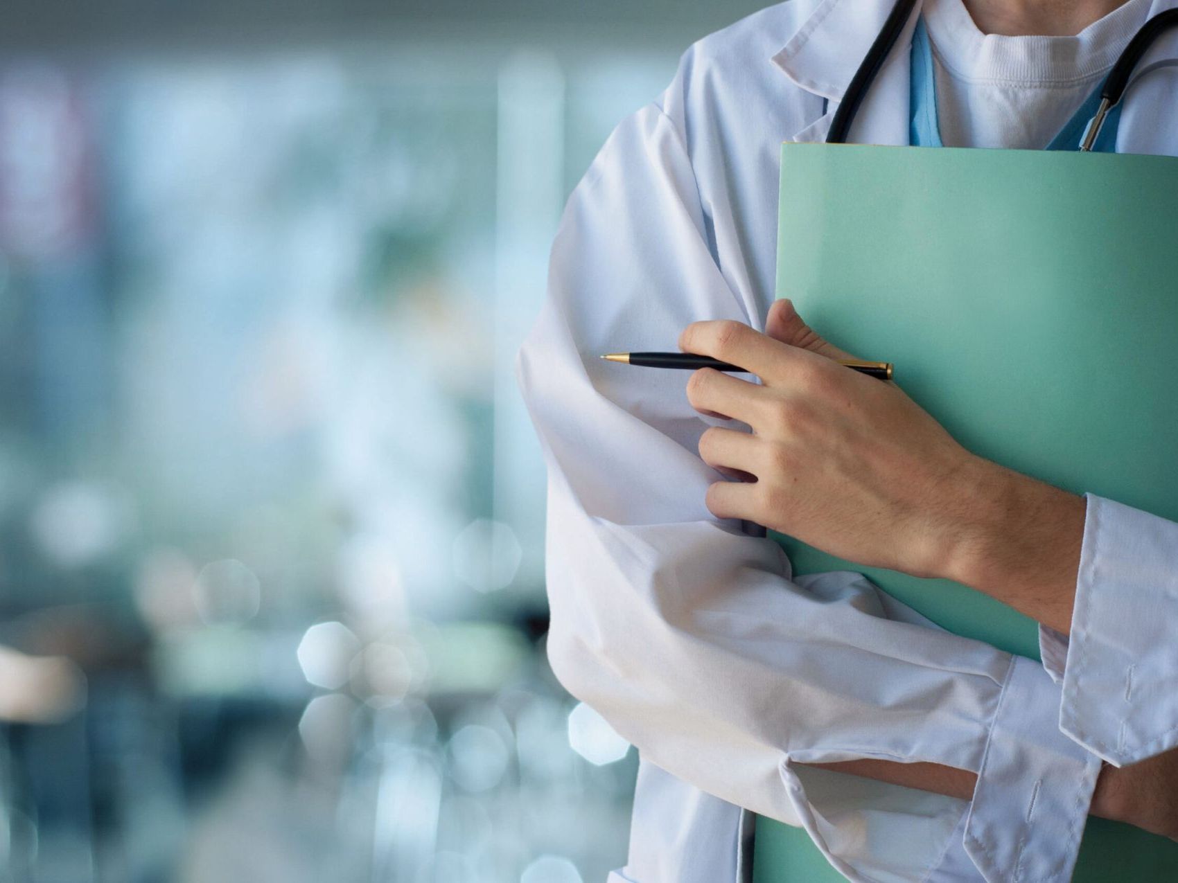 A close-up of a doctor holding a clipboard and a pen.