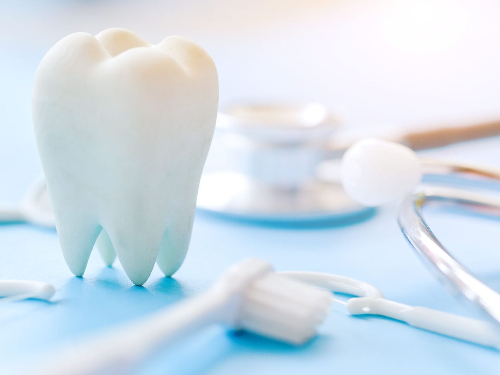 A tooth is sitting on a table next to toothbrushes and a stethoscope.