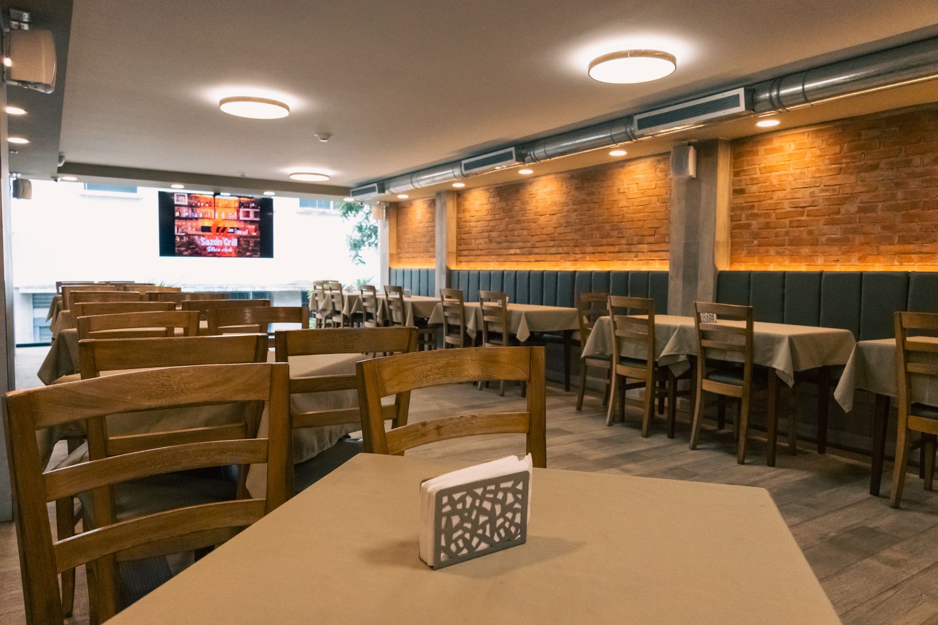 A restaurant with tables and chairs and a tv on the wall.