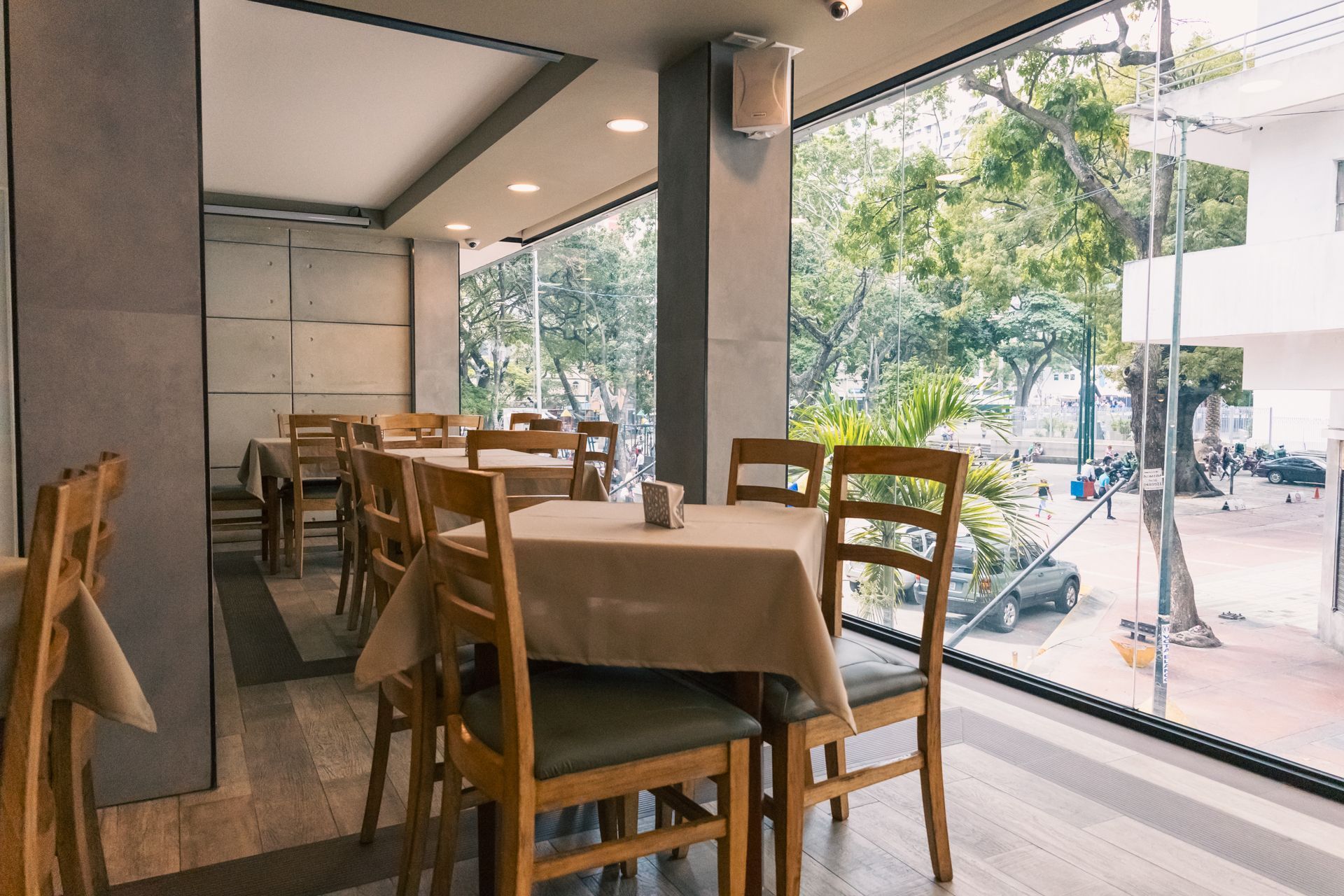 A restaurant with tables and chairs and a large window.