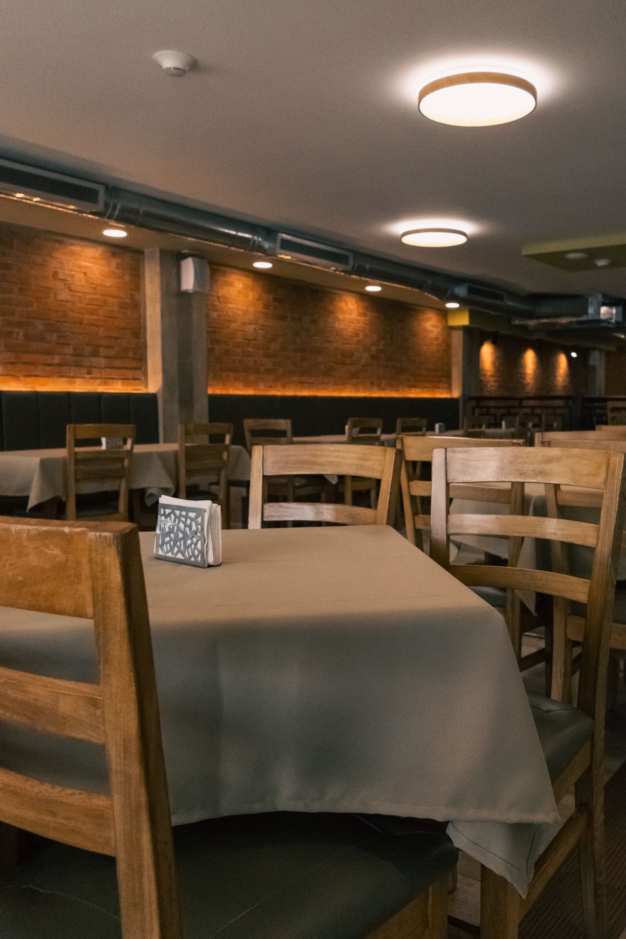 A restaurant with tables and chairs and a napkin holder on the table