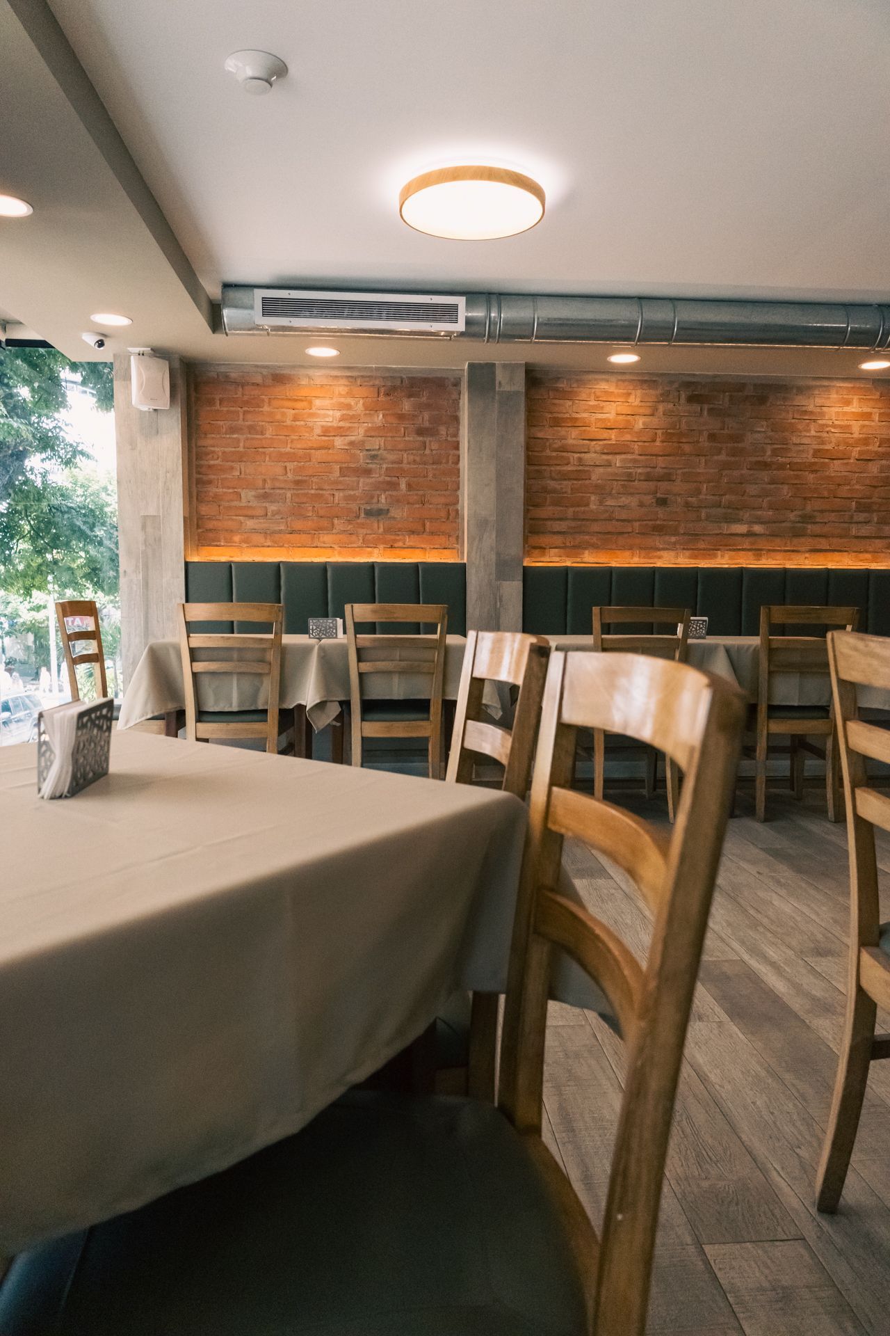 A restaurant with tables and chairs and a brick wall.