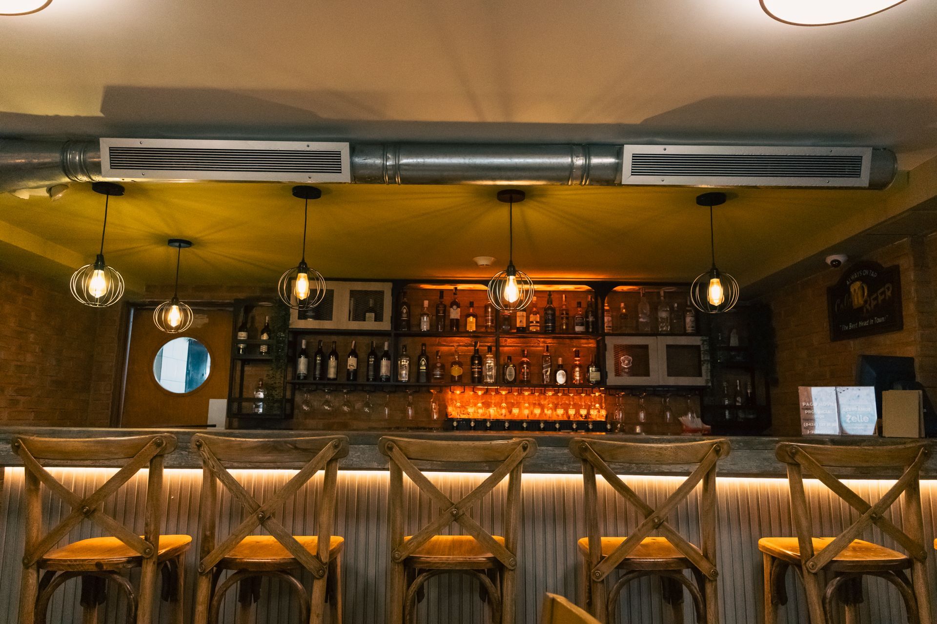 A bar with a lot of bottles on it and stools.