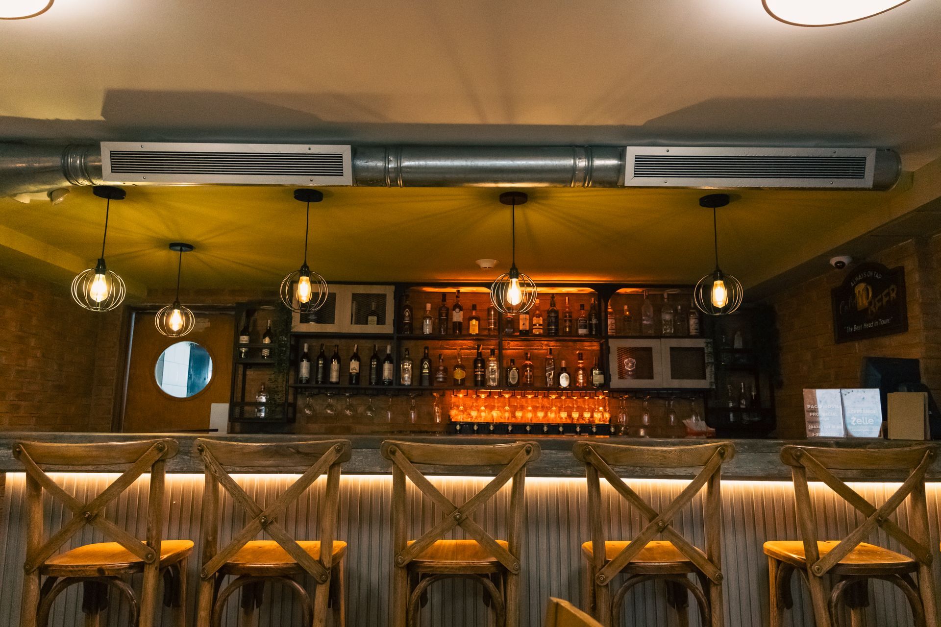 A bar with a lot of bottles on it and stools