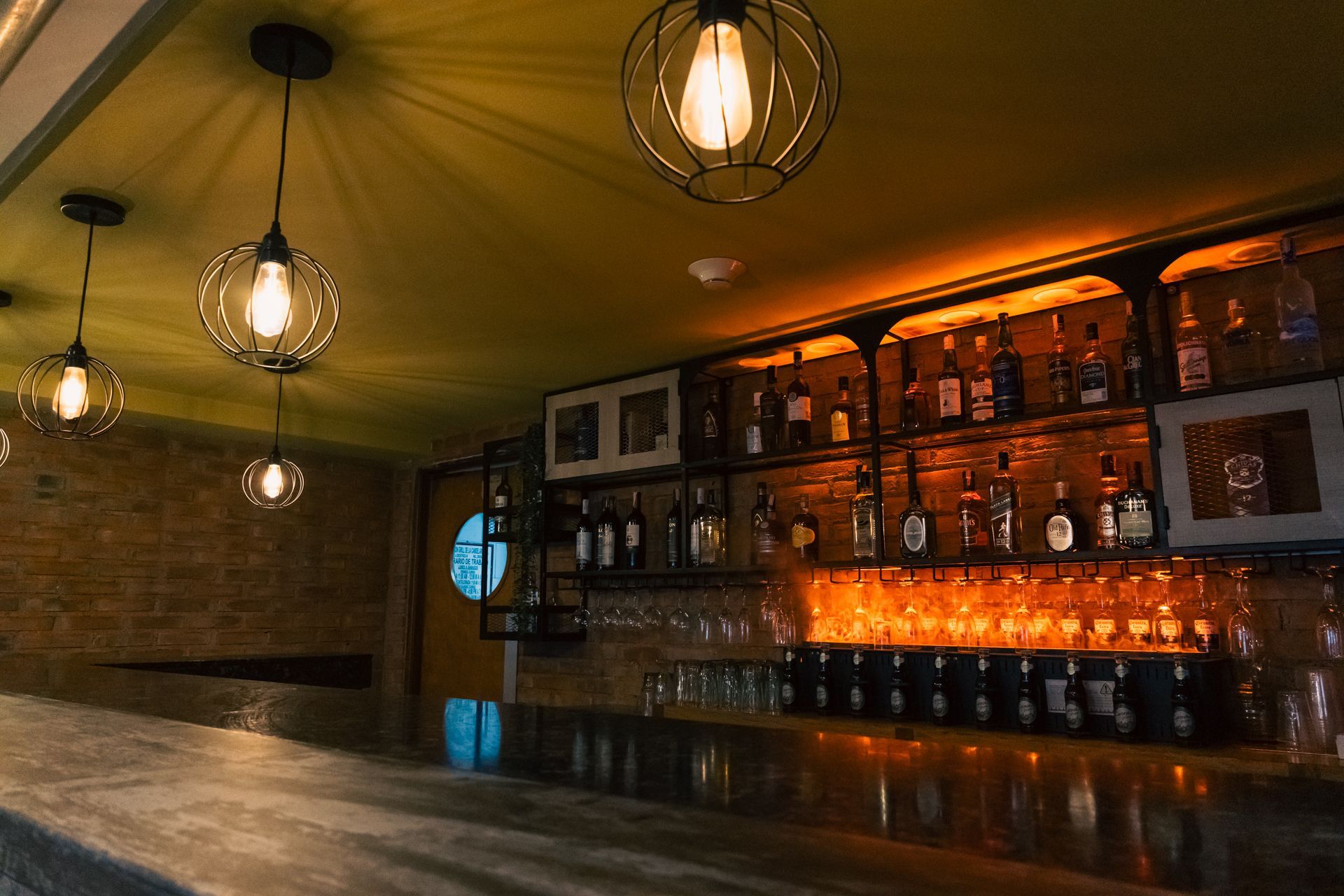 A bar filled with lots of bottles of alcohol and glasses.